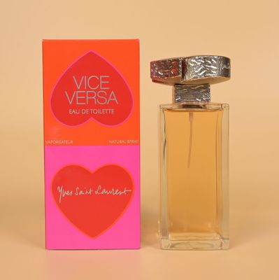une photo représentant un flacon de parfum posé sur une table, accompagné d'un coffret rose