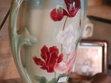 a white vase with red flowers on it on a table