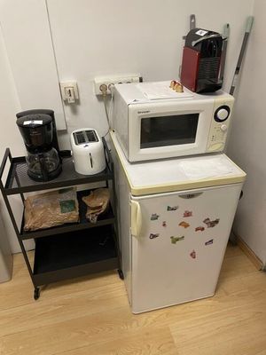 two microwaves and a coffee maker in a small kitchen