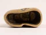a small bronze figurine of a shoe on a white surface