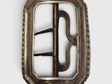 une boucle ancienne en argent sur fond blanc, accompagnée d'une photo en noir et blanc