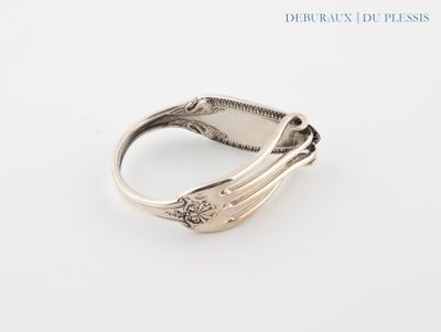 gros plan d'une bague en argent sur une surface blanche