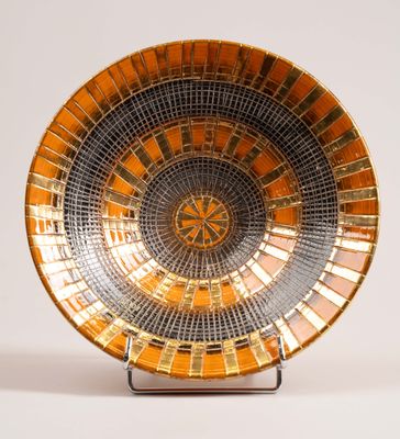 a gold and black bowl on a stand on a white surface