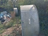 une poubelle posée au bord de la route, près d'un buisson