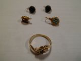 trois bagues et deux boucles d'oreilles posées sur une surface blanche
