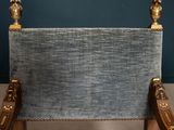 a chair that has a blue upholstered seat with gold accents