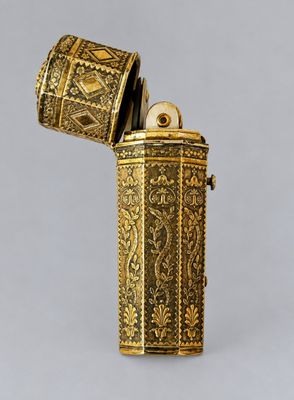 an antique gold lighter with a metal case on a gray background