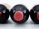three bottles of wine are lined up in a row on a white surface