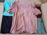 une boîte en carton posée par terre et contenant des vêtements
