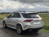 the rear end of a silver mercedes suv parked on the side of a road