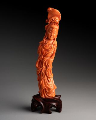une statue sculptée dans de l'orange représentant une femme, posée sur un socle en bois