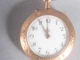a gold pocket watch with a white face hanging from a rope