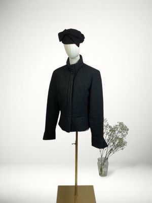 jacket on a mannequin stand with a vase of flowers in the background