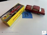 une petite voiture rouge posée à côté d'une boîte jaune sur une table