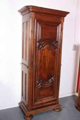 a tall wooden cabinet in the corner of a room