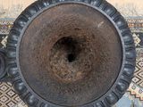 a black vase sitting on top of a rug on a wooden floor