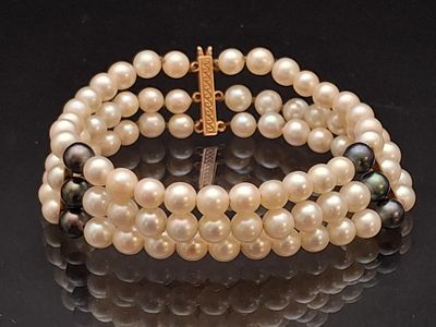 a bracelet with pearls and a gold clasp on a black surface
