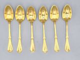 six gold spoons and spoon spoons are lined up on a gray surface