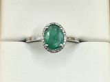 an emerald and diamond ring in a box on a white surface