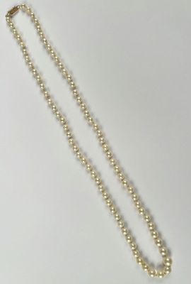 a close up of a necklace with pearls on a white surface