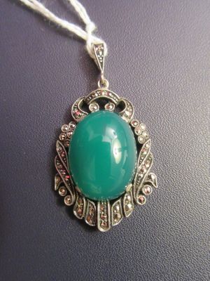 an image of a necklace with a green stone on it