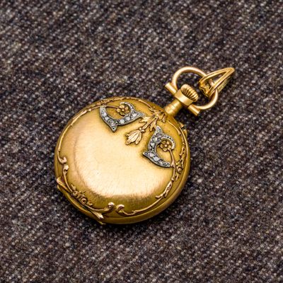 une petite montre de poche en or ornée d'un oiseau