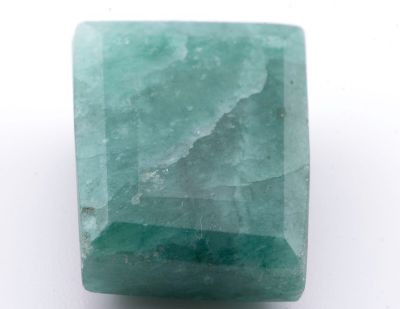 un gros plan d'une pierre verte sur une surface blanche