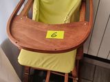 une chaise haute en bois avec un siège jaune, placée devant une porte