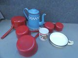 une théière bleue et des casseroles et poêles rouges posées sur une table