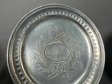 an antique silver plate with a crown and laurel on it