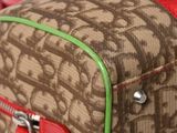a brown and green bag with a red handle