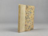 un vieux livre posé sur une table blanche à côté d'un mur gris
