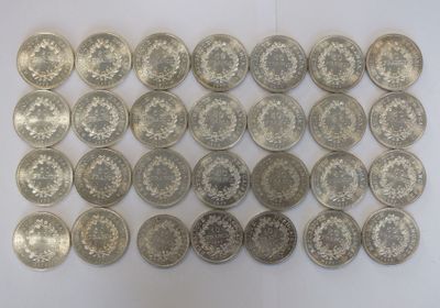Plusieurs pièces d'argent sont disposées en rangées sur une surface blanche