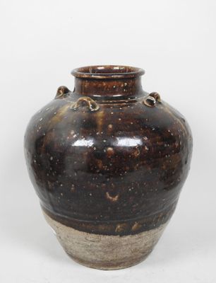 un vase marron posé sur une surface blanche