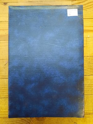 un livre bleu posé sur un parquet, à côté d'une table en bois