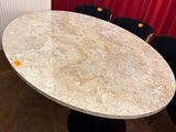 une table et des chaises en marbre dans une pièce aux rideaux rouges