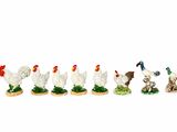 cinq figurines représentant des poulets et un chien, alignées les unes à côté des autres