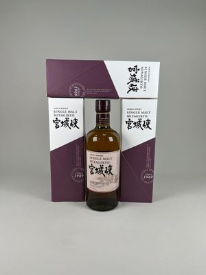 une bouteille de whisky japonais devant une boîte violette et blanche
