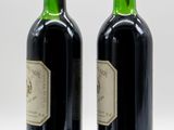 two bottles of wine sitting next to each other on a white surface