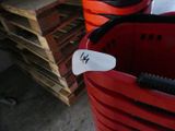 a red bucket with a tag on it next to a stack of pallets