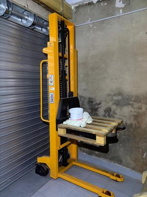 a forklift with a coffee cup on it in front of a garage door