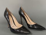 a pair of black high heeled shoes on a grey surface