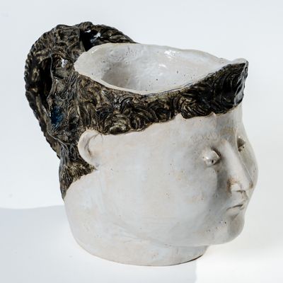 un vase blanc surmonté d'une tête noire