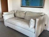 a white couch in a living room with a painting on the wall
