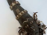 un objet en bois orné de plumes, posé sur une surface blanche