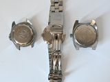 three watches are sitting on a white surface with a white background