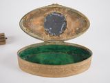a small gold box with a black stone in it