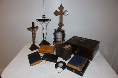 a small table with a clock, books, and a crucifix on it