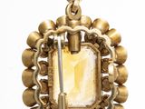 a close up of a gold necklace with a stone in the center