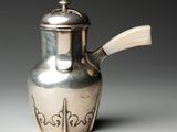 une théière ancienne en argent, dotée d'une poignée en bois sur un fond blanc